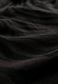 Tissu noir doux avec des plis subtils et une surface légèrement texturée, présenté en gros plan.