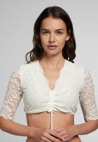 Weißes Spitzen-Croptop mit ellbogenlangen Ärmeln, das an der Vorderseite gerafft ist und einen Kordelzug entlang des unteren Saums hat. Mit gewelltem Ausschnitt.