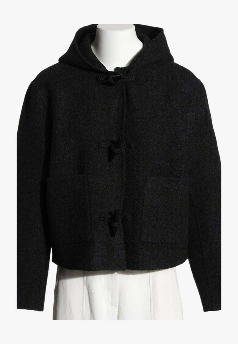 Veste noire en laine avec capuche, fermetures à boutons à bascule et deux poches plaquées à l'avant sur un torse de mannequin blanc.