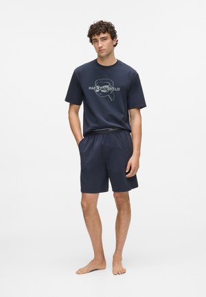 Tengeréskék otthoni viselet szett, amely egy rövid ujjú pólóból áll grafikus nyomattal és azonos színű, elasztikus derekú sortokból. Puha szövet textúra.