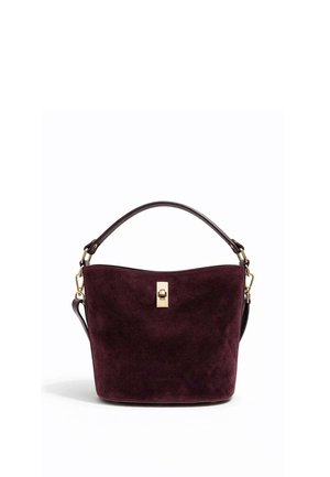 Sac seau en daim violet foncé avec poignée courte, fermoir doré et bandoulière amovible sur fond blanc.