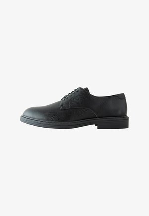 Zwarte, gestructureerde leren heren veterschoen met lage hak en ronde neus, getoond vanaf de buitenkant op een witte achtergrond.