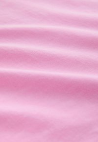 Tissu rose doux avec de légers plis et une texture de tissage fin visible.