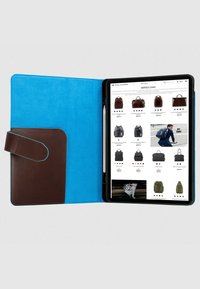 Tablethoes met een blauwe suède binnenkant en een bruine leren zak en sluiting. Op het scherm worden verschillende rugzakopties op een website weergegeven.