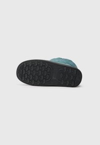 Obutev z črnim gumijastim podplatom in teksturiranim vzorcem, ki ima teal zgornji del z quilted designom. Ravna, sproščena oblika.