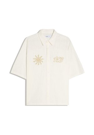 Fehér, rövid ujjú, gombos galléros ing, bal mellrészen nap mintával, jobb mellrészen sárga hímzésű 146-os számmal.