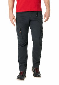 Schwarze Cargo-Hosen mit mehreren Seitentaschen und lockerer Passform, kombiniert mit dunklen Schuhen mit roten Schnürsenkeln, getragen mit einem roten Hemd.