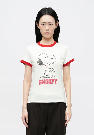 Maglietta bianca a maniche corte con dettagli rossi, caratterizzata da una grafica di Snoopy e dalla scritta "SNOOPY" in rosso. Tessuto morbido con una vestibilità comoda.