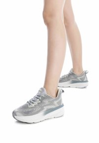Zapatillas deportivas grises con un upper texturizado, diseño de cordones y una gruesa suela blanca con una banda de acento gris claro.