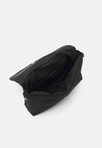 Black clutch bag with a soft, smooth texture, zip closure, and spacious interior. Features a label inside and minimal hardware accents.