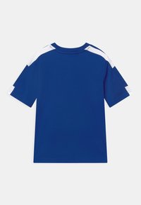 Modrá tričko s krátkým rukávem, které má kontrastní bílé akcenty na ramenou. Hladká látka a kulatý výstřih s rovně střiženým designem.