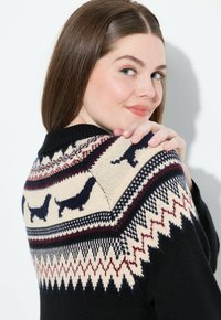 Schwarzer Pullover mit einem cremefarbenen geometrischen Einsatzdesign und Dackelmotiven, akzentuiert in Marineblau und Bordeaux. Glatte Textur, leichtes Strickmaterial.