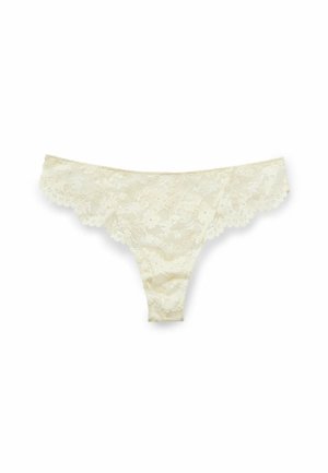 Lace thong in light cream, featuring floral patterns and scalloped edges. Soft texture with a minimalist design and a high-cut shape.