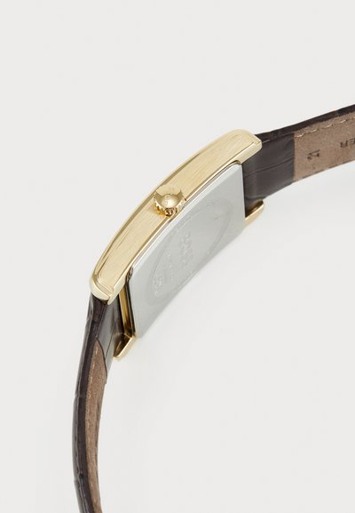 Montre rectangulaire en or avec un boîtier en argent, un bracelet en cuir marron et une couronne texturée. Comprend des détails gravés à l'arrière.