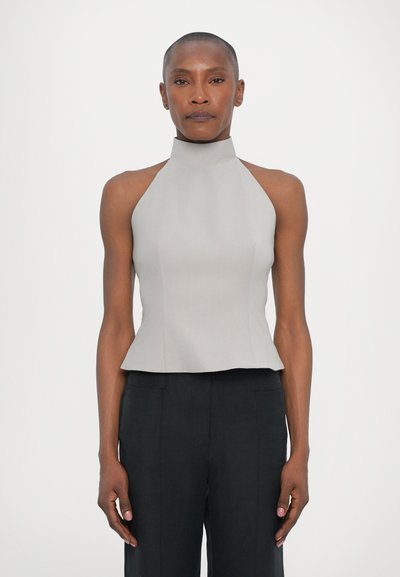 Šedý halter top z pevného materiálu s přiléhavým korzetem, peplum spodním lemem a bez viditelných vzorů. V kombinaci s tmavými kalhotami.