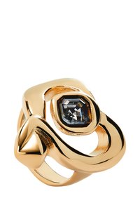 Bague dorée à la tonalité fluide, présentant une pierre précieuse octogonale sombre au centre, accentuée par un point triangulaire. Surface lisse et réfléchissante.