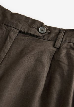 Dark brown linen trousers featuring a button closure, front pleats, and a smooth texture. Visible stitching around the waist and button.