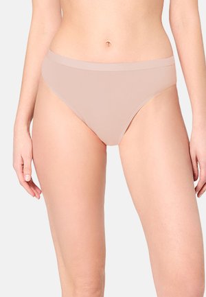 Woman wearing seamless nude-colored mid-rise bikini underwear, shown from mid-torso to mid-thigh against plain background.
