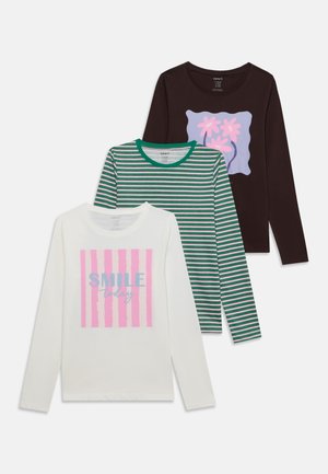 Trois chemises à manches longues pour enfants : blanche à rayures roses avec le texte "SMILE today", rayures vertes et blanches, et noire avec un motif fleur rose.