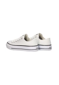 Zapatillas de lona blancas, con punteras redondas, cierre de cordones, rayas negras en la suela y una puntera de goma reforzada.