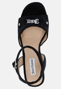 Sandalo con zeppa in suede nero, con una fascia larga, decorazione con logo argentato e cinturino alla caviglia. La suola è beige con etichetta del marchio.