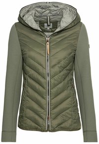 Giacca a vento verde oliva con cappuccio e chiusura con zip, caratterizzata da un motivo a chevron trapuntato sul corpo e maniche in tinta unita, realizzata con materiali riciclati.