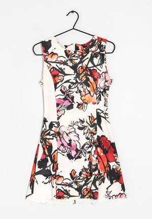 Robe blanche sans manches avec un motif floral abstrait coloré en rouge, orange, rose et noir, suspendue sur un cintre noir.