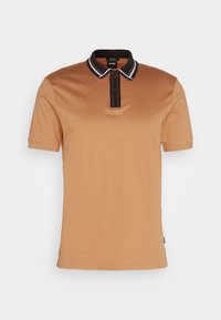 Polo à manches courtes pour homme en couleur beige avec un col noir ornée de rayures blanches et une patte de boutonnage à deux boutons.