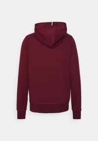 Sweat à capuche à manches longues de couleur rouge foncé avec des poignets et une ceinture côtelés, doté d'une capuche avec une petite languette en tissu rayé à l'arrière.
