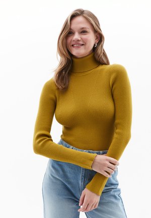 Senfgelbes, geripptes Rollkragensweatshirt mit langen Ärmeln, strukturiertem Stoff, körpernahem Design und weichem Finish, kombiniert mit hellblauen Jeans.