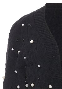 Cardigan nero lavorato a maglia con design a trecce, arricchito da perle finte nere e bianche sparse per un tocco di texture.