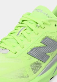 Neon green athletic shoe with textured upper, grey accents, and logo. Features flat laces and a lightweight design for performance.