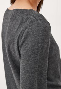 Maglione grigio con scollatura a coste e texture liscia, con un design aderente che si adatta alla spalla e alla parte superiore del braccio.