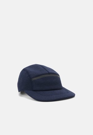 Casquette en tissu bleu foncé avec une visière incurvée et un détail de bande noire horizontale sur le panneau avant, posée sur un fond clair uni.