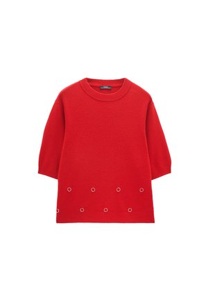 Czerwony sweter z krótkim rękawem, okrągłym dekoltem i ośmioma równomiernie rozmieszczonymi małymi metalowymi kółkami w pobliżu dolnego brzegu.