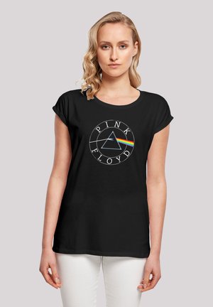 Schwarzes T-Shirt mit einem runden Logo, das den Text "PINK FLOYD", ein Dreieck und einen Regenbogenstreifen auf einer weichen Textur zeigt. Kurzärmelig.
