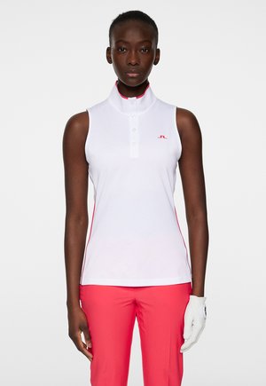 Polo sans manches blanc avec un col montant, présentant une accent rouge sur les côtés et une fermeture à trois boutons, associé à un pantalon rose.