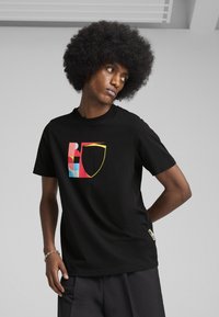 Sort bomulds T-shirt med et flerfarvet grafisk design med former i rødt, blåt og gult. Korte ærmer og afslappet pasform.