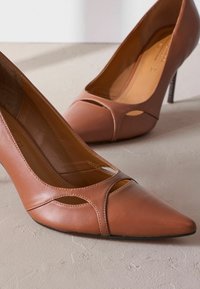 Ruske nahkakengät korkealla korolla, terävämpipäinen ja leikatuilla kuvioilla. Varustettu ohuella nilkkahihnalla ja korkealla stiletto-korolla. Smooth pinta.