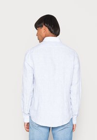 Camicetta a maniche lunghe a righe blu e bianche con colletto classico, polsini con bottoni e orlo arrotondato. Il materiale sembra leggero e strutturato.