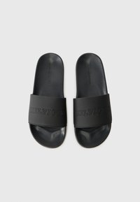 Black slide sandals with a textured leather band. "HILFIGER" embossed on the strap. Rounded toe and contoured footbed. Matte finish.