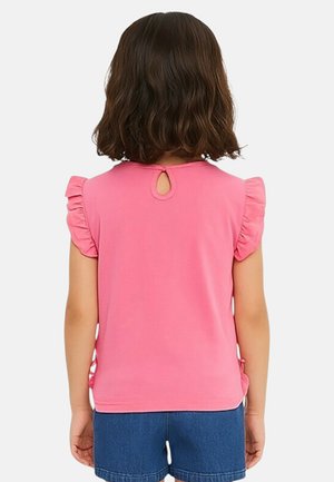 Haut rose à manches courtes avec manches à volants, présentant une découpe en forme de trou de serrure dans le dos et une texture légère et lisse. Associé à un short en denim.