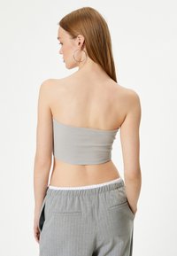 Top bandeau gris acanalado con un corte horizontal, combinado con pantalones gris de rayas con una cinturilla elástica y bolsillos laterales.