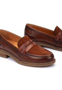Mocasines de cuero marrón con detalles de ante, que cuentan con un acabado suave, costuras en contraste y una suela de goma baja y ligeramente texturizada.