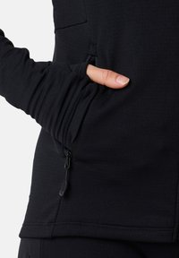 Svart, elastisk långärmad topp med en dragkedja i sidan och tumhål i ärmarna, som har en slät yta och en figurnära design.