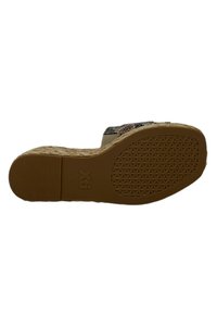 Suela de goma marrón con un patrón texturizado, que presenta un ligero tacón y un diseño superior tejido detallado, destacando una paleta de colores neutros.