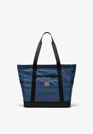 Sac fourre-tout bleu avec anses et base noires, poche frontale rectangulaire et petite étiquette de marque marron centrée sur le devant.