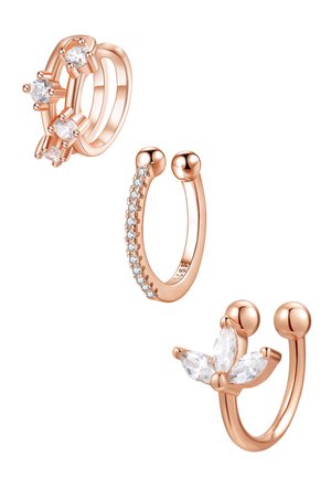 Woman's ear with three rose gold earrings: a twisted hoop on the upper ear, a small crystal cluster in the middle, and a thin band on the earlobe.