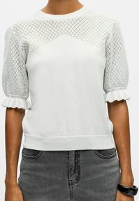 Pull blanc avec des manches en maille texturée à motif en diamant, doté de poignets et d'un ourlet côtelés. Le corps a une finition lisse.