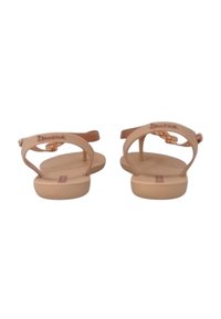 Sandali nudi con suola piatta, design a T-strap e chiusura con fibbia. Realizzati in materiale sintetico, presentano una texture liscia e opaca.